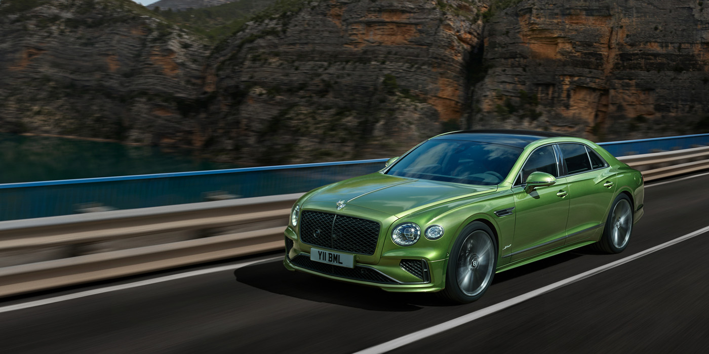 Bentley Tbilisi Bentley New Flying Spur Speed v8 hybrid sedan driving dynamically on a mountain road in Tourmaline Green paint