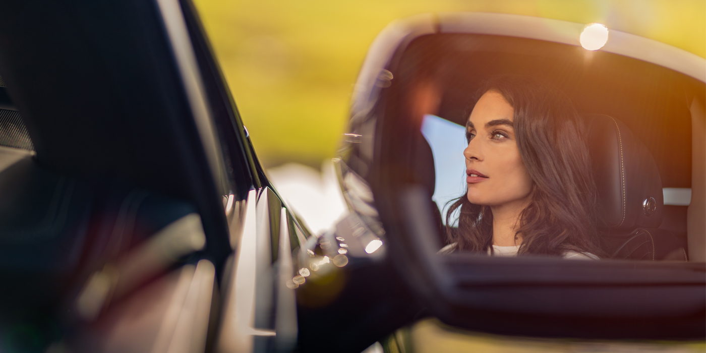 Bentley Tbilisi profile of dark haired woman's face in mirror of Bentley car in sunlight