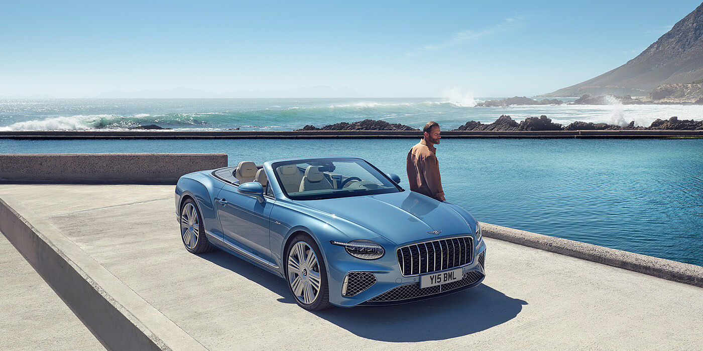 Bentley Tbilisi New Bentley Continental GTC Azure convertible front view in Light Windsor blue paint with 22 inch ten spoke wheels parked by the sea in the sunshine