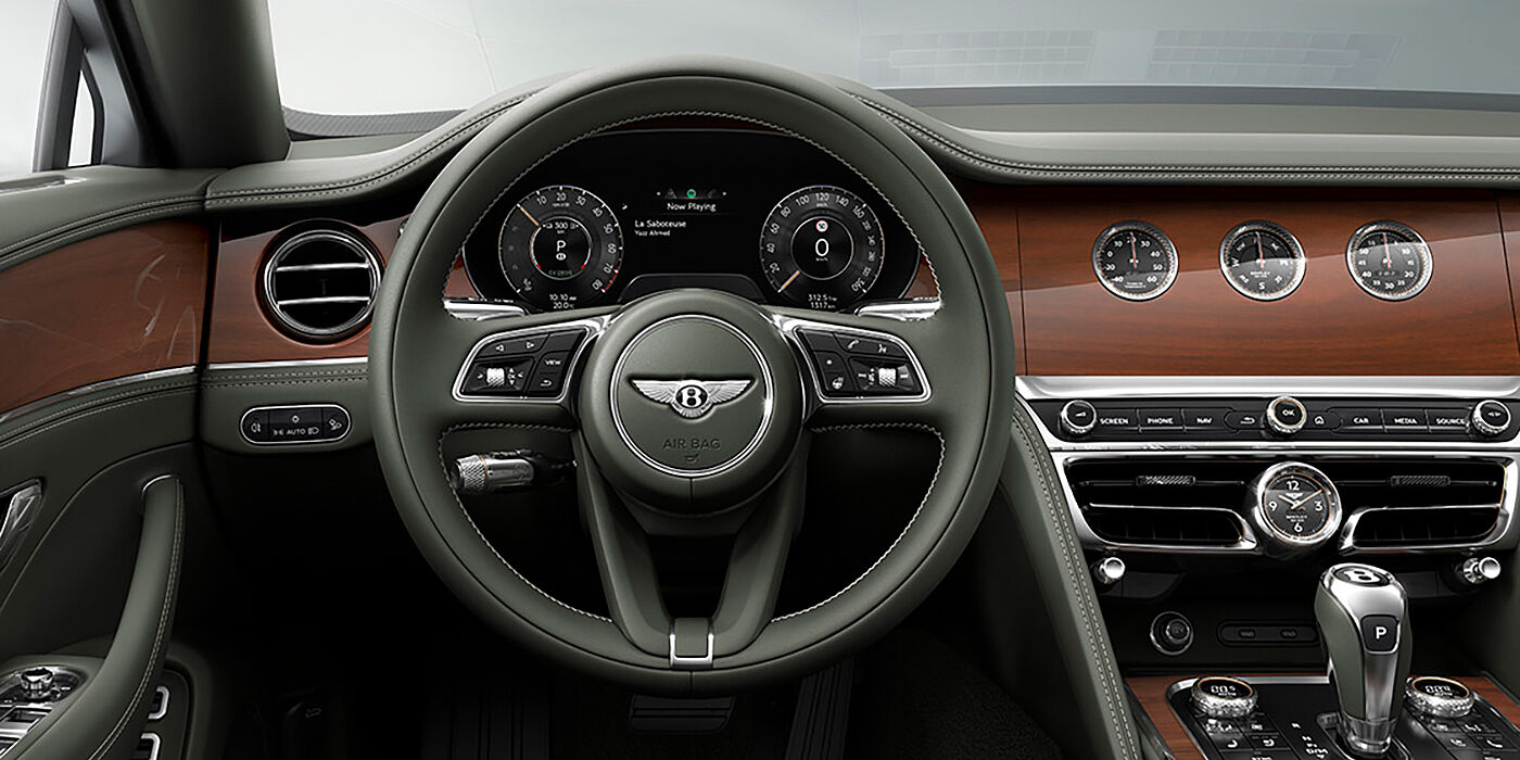 Bentley Tbilisi New Bentley Flying Spur sedan front cabin in Cumbrian Green hide and Crown Cut walnut veneer showing steering wheel and Rotating Display with three clocks on face